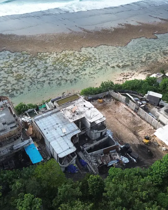 Bangunan Home Cliff di tepi tebing menghadap pantai, dengan alat berat di area kerja